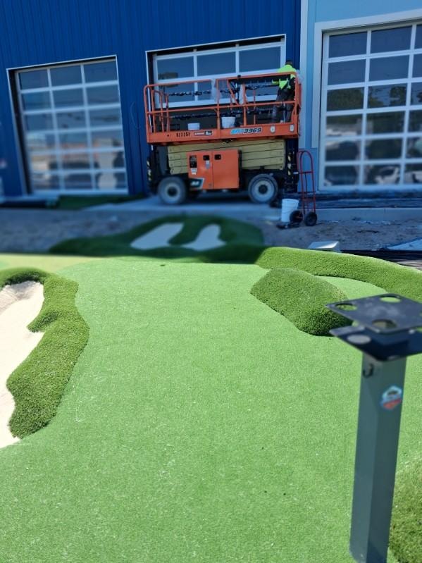 Mini golf course with scissor lift backdrop